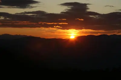 a sunset over the mountains with the sun in the sky at Mühlerhof in Funes