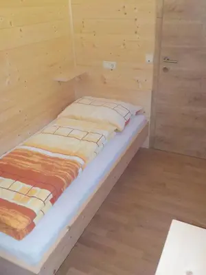 a small bed in a room with wooden walls at Berghütte Plafötschalm in Tires