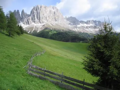 a field with a fence in front of a mountain at Berghütte Plafötschalm in Tires