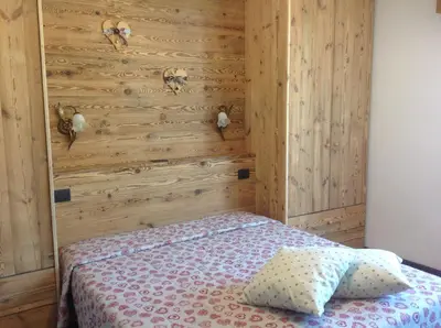 a bedroom with a wooden wall with a bed at Casa Berlanda in Fiera di Primiero