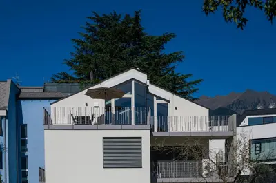 a white building with a balcony with an umbrella at Villa Camilde - elegance and relax in Merano in Merano