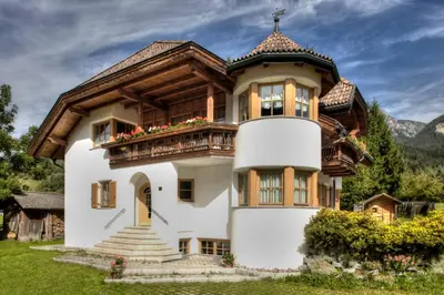 a house in the mountains with a balcony at Alexander Mountain-Lodge in San Vigilio Di Marebbe