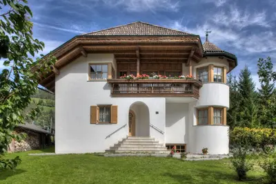 a large white house with a balcony at Alexander Mountain-Lodge in San Vigilio Di Marebbe