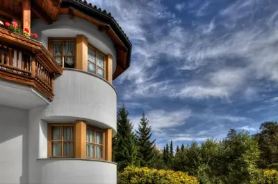 a building with a balcony and a blue sky at Alexander Mountain-Lodge in San Vigilio Di Marebbe
