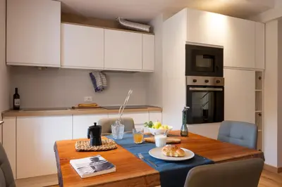 a kitchen with a wooden table and white cabinets at SnowLake Suite & Apartment in Alleghe