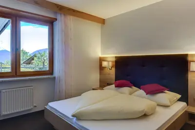a bedroom with a bed with white sheets and red pillows at Residence Krone in Schenna