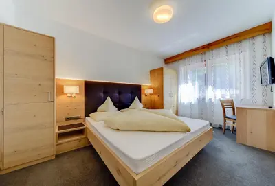 a bedroom with a large bed and a desk at Residence Krone in Schenna