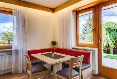 a dining room with a table and chairs and windows at Residence Krone in Schenna