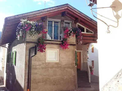 a house with flowers on the side of it at Casa vacanze Maria in Tesero