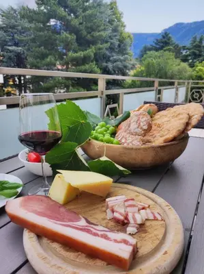 a table with a plate of food and a glass of wine at Apartment Alpenflair City Meran in Merano