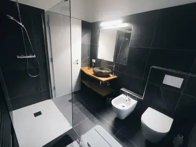 a bathroom with a sink and a toilet and a mirror at Apartment Alpenflair City Meran in Merano