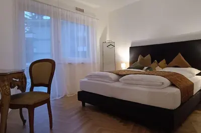 a bedroom with a bed and a desk and a chair at Apartment Alpenflair City Meran in Merano