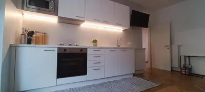 a kitchen with white cabinets and a stove top oven at Apartment Alpenflair City Meran in Merano