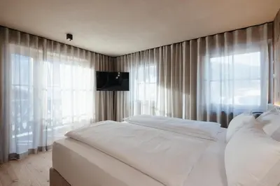 a bedroom with a white bed and a window at Pescosta Chalet Luxury Living in San Vigilio Di Marebbe