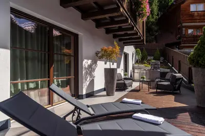 an outdoor patio with lounge chairs and a table at Pescosta Chalet Luxury Living in San Vigilio Di Marebbe