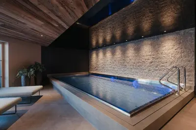 a large swimming pool in a room with a brick wall at Pescosta Chalet Luxury Living in San Vigilio Di Marebbe