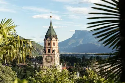 a building with a clock tower with a mountain in the background at Apartment Anna in Merano