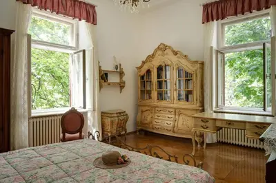 a bedroom with a bed and a desk and windows at Apartment Anna in Merano