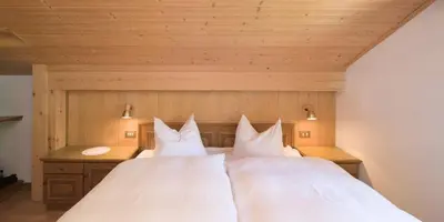 a large bed with two white pillows on it at Apartments Stroblhof in Ortisei