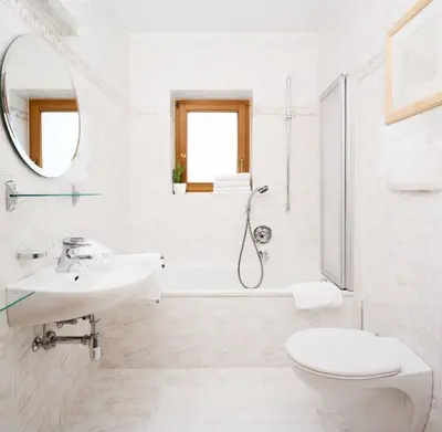 a white bathroom with a sink and a toilet at Apartments Stroblhof in Ortisei