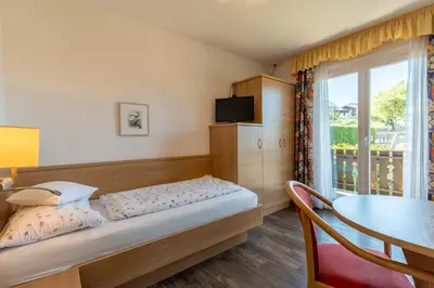 a bedroom with a bed and a table and a window at Garni Dürrenstein in Schenna