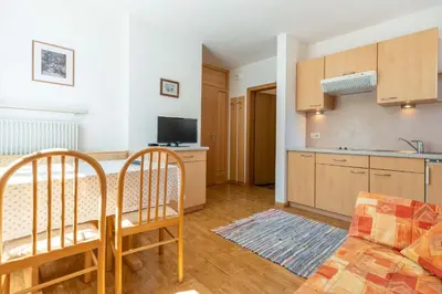 a kitchen and a living room with a table and chairs at Garni Dürrenstein in Schenna