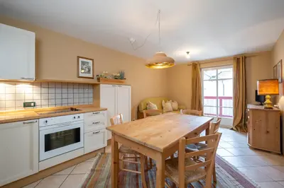 a kitchen with a wooden table and a dining room at Ciasa Buro - Thaus in Moena