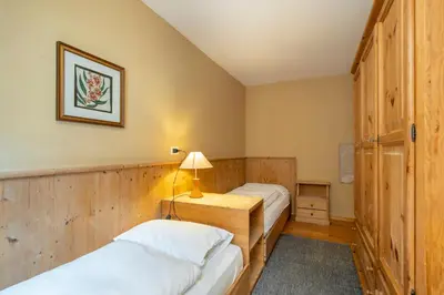 two twin beds in a room with wooden walls at Ciasa Buro - Thaus in Moena
