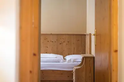a bedroom with a wooden bed with white sheets and pillows at Ciasa Buro - Thaus in Moena