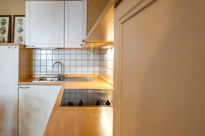 a kitchen with white cabinets and a sink at Ciasa Buro - Thaus in Moena