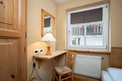 a bedroom with a desk and a window with a lamp at Ciasa Buro - Thaus in Moena