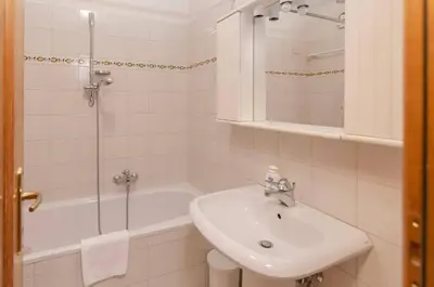 a white bathroom with a sink and a bath tub at Cà Enrosadira primo piano in San Vito di Cadore