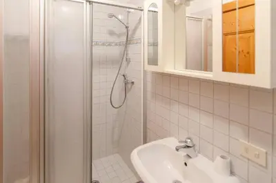 a white bathroom with a shower and a sink at Cà Enrosadira primo piano in San Vito di Cadore