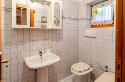 a white bathroom with a sink and a toilet at Cà Enrosadira primo piano in San Vito di Cadore