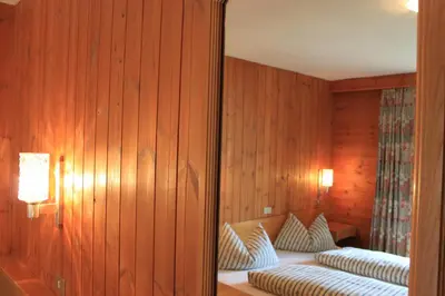 a mirror in a room with a bed with pillows at Albergo Alisander in Corvara in Badia