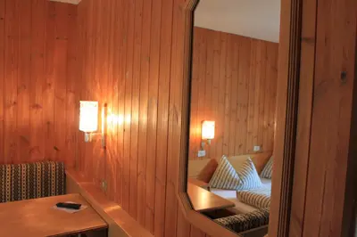 a mirror in a room with a bed with pillows at Albergo Alisander in Corvara in Badia