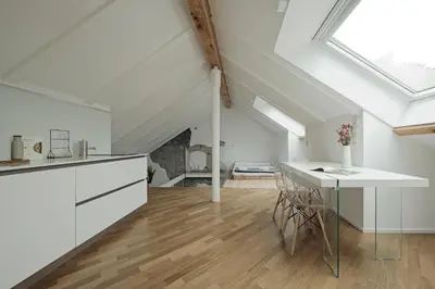 a kitchen with white cabinets and a table in a attic at Historic Rooms and Apartments in the City Centre of Bolzano in Bolzano
