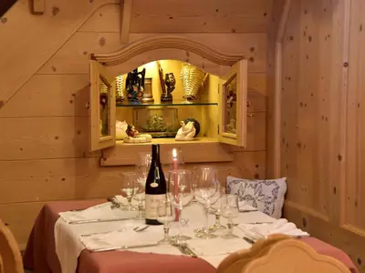 a dining room with a table with a bottle of wine at Rifugio Capanna Passo Valles in Falcade