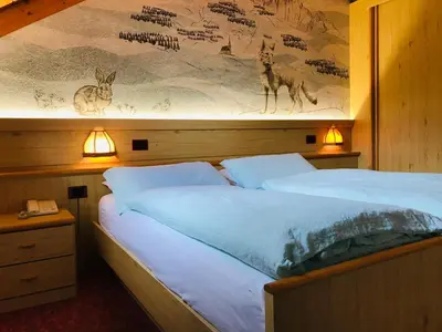 two beds in a bedroom with two lights on the wall at Rifugio Capanna Passo Valles in Falcade