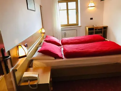 a bed with red sheets and pillows on it at Rifugio Capanna Passo Valles in Falcade