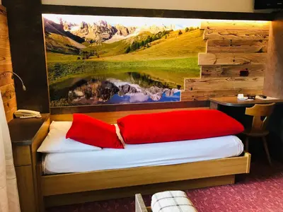 a room with a bed with red pillows and a painting at Rifugio Capanna Passo Valles in Falcade