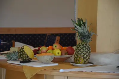 a table topped with bowls of fruit and a pineapple at Hotel Greifenstein in Terlano