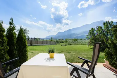 a table and chairs on a patio with a view of a yard at Hotel Greifenstein in Terlano