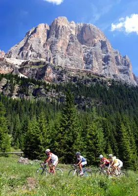 three people riding bikes in front of a mountain at Ciasa Vervei in Cortina dʼAmpezzo