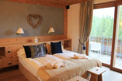 a bedroom with a large bed and a balcony at Ciasa Vervei in Cortina dʼAmpezzo