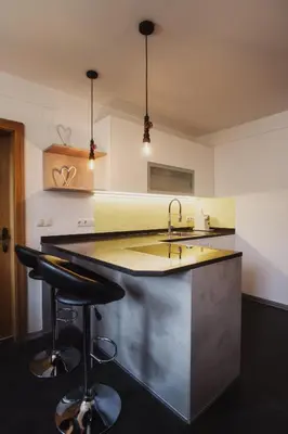 a kitchen with a sink and two bar stools at Töllhof Studio Stube in Bressanone