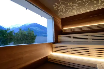 a sauna with a large window and a mountain view at Hotel Ifinger in Schenna