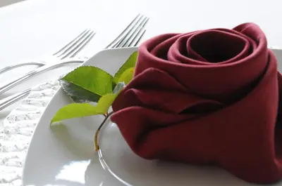 a red rose sitting on a plate with fork at Hotel Ifinger in Schenna