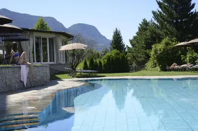 a woman sitting on a wall next to a swimming pool at Hotel Ifinger in Schenna