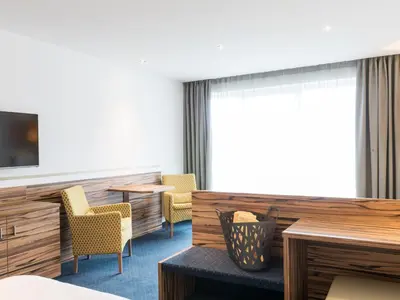 a room with chairs and a table and a tv at Hotel Ifinger in Schenna